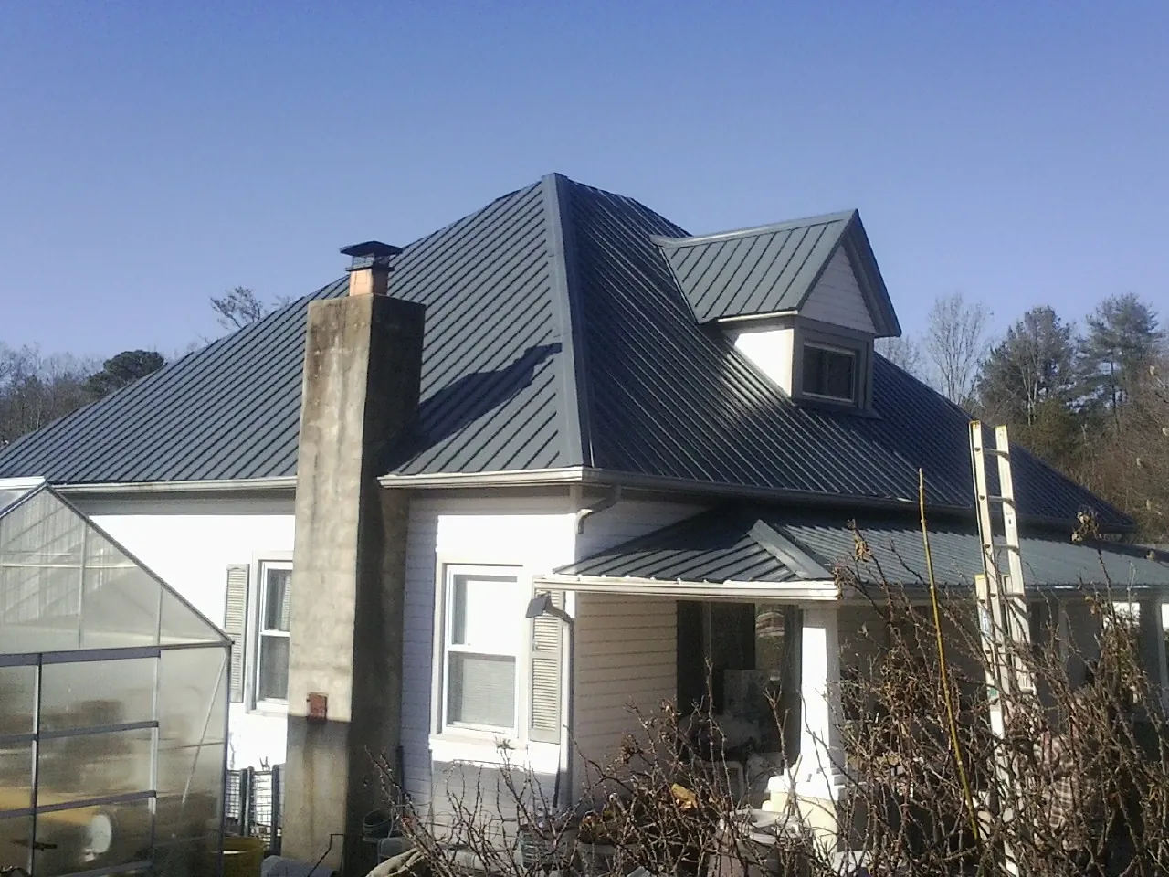 Dark blue standing seam metal roof on a white farmhouse with dormer — Slate & Tile Roof Repair by Roofing Brothers in Crimora