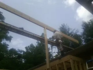 Carpenter setting a ridge beam over a new addition frame — Ice Dam Removal by Roofing Brothers in Crimora