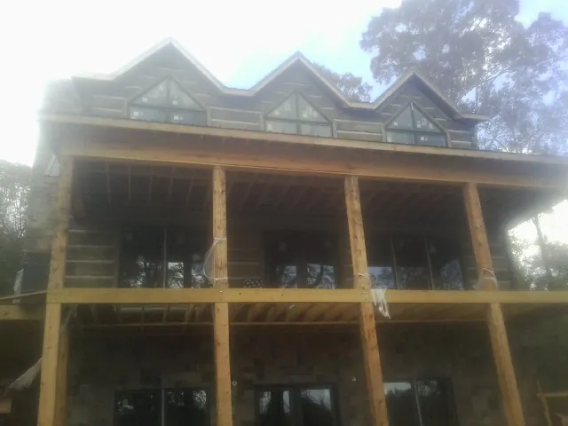 Dormers and porch framing on a large log home under construction — Roof Coating work by our crew in Crimora