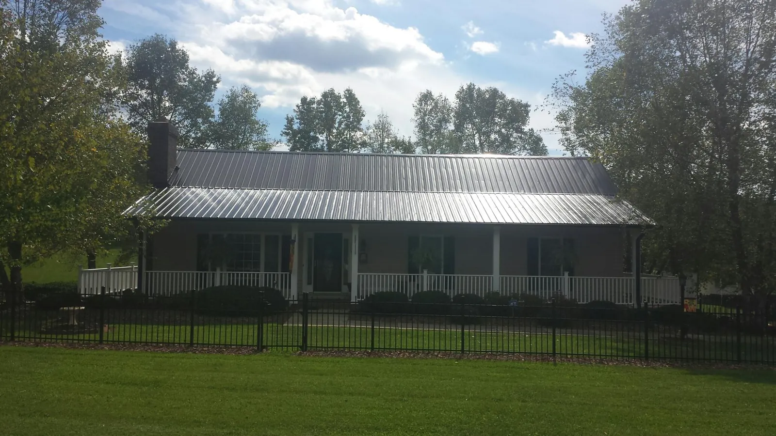 Gray metal roof on a brick ranch with a full width front porch — Gutter Guard Installation work by our crew in Crimora