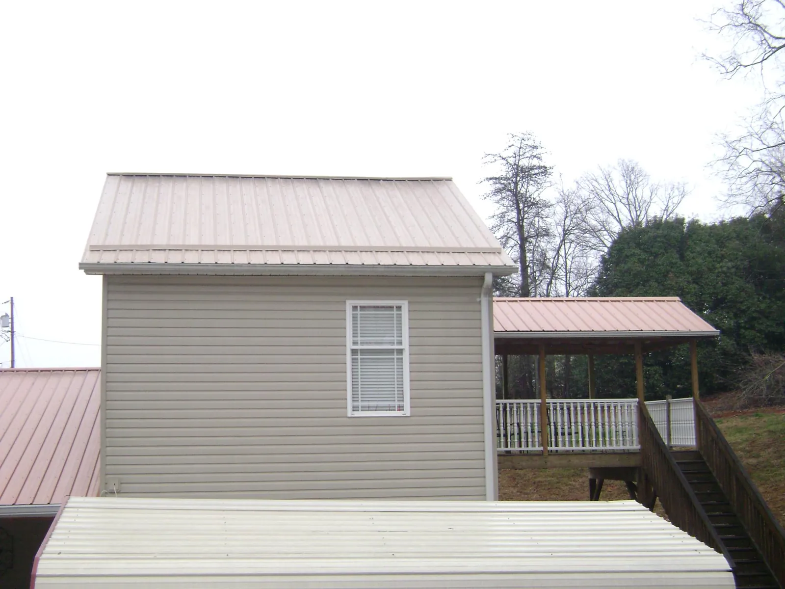 Tan metal roofs on a two story addition and attached porch, from a Roof Replacement job in Crimora