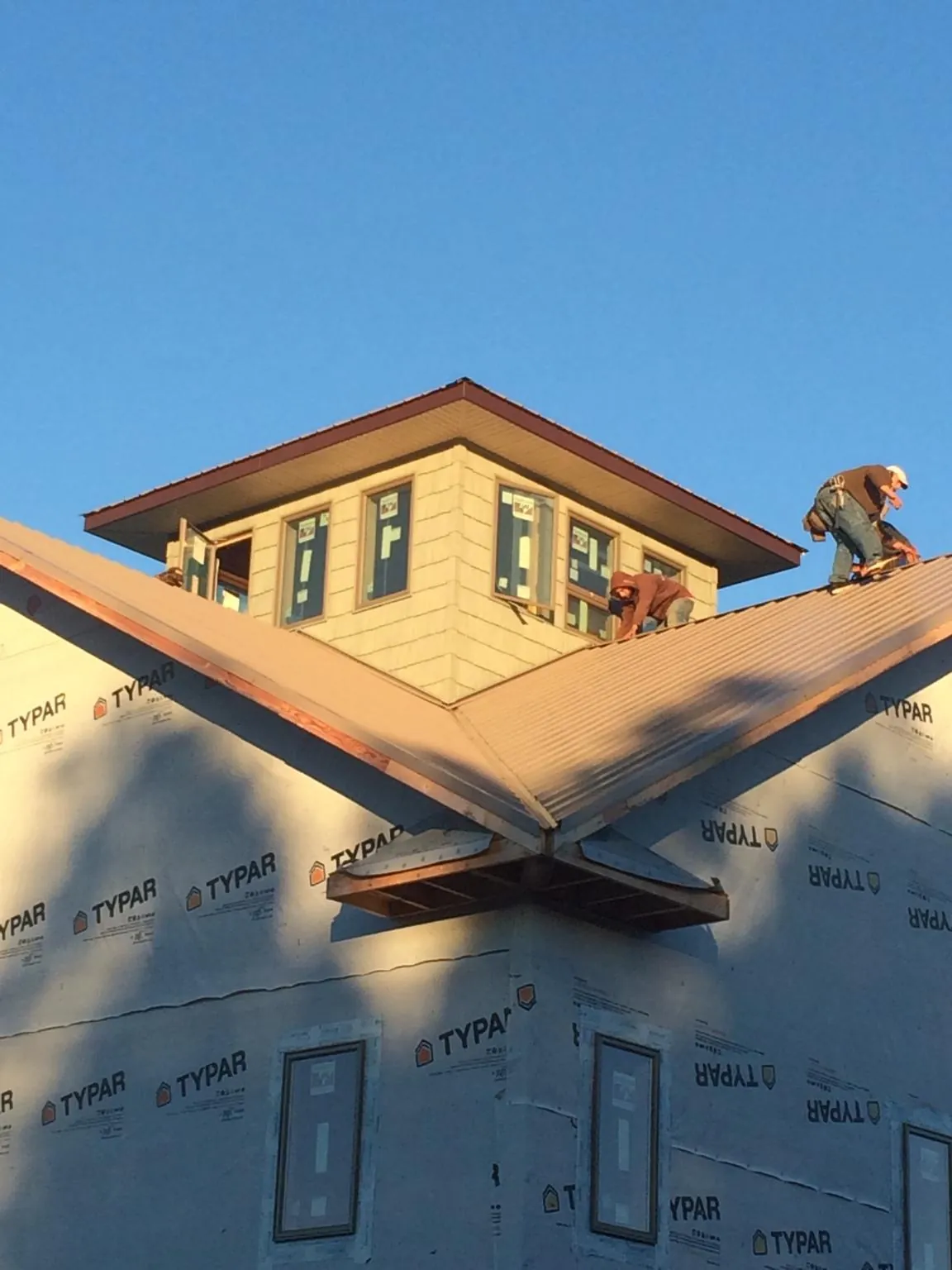 Roofers working around a rooftop cupola on a new metal roof at sunset — Roof Waterproofing in Crimora by Roofing Brothers